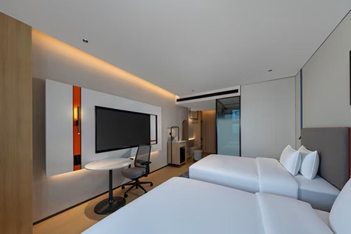 Habitación de hotel moderna con una cama grande, un escritorio y un televisor de pantalla plana montado en la pared.