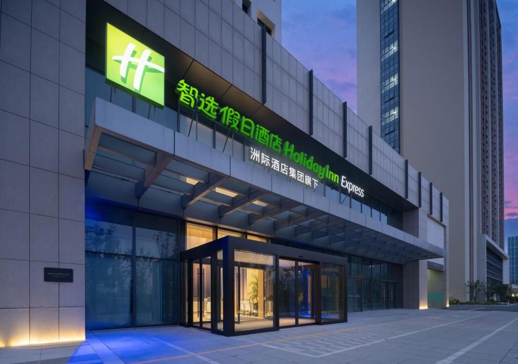 A modern hotel entrance with a glass facade and a sign indicating it's part of the Holiday Inn Express chain.