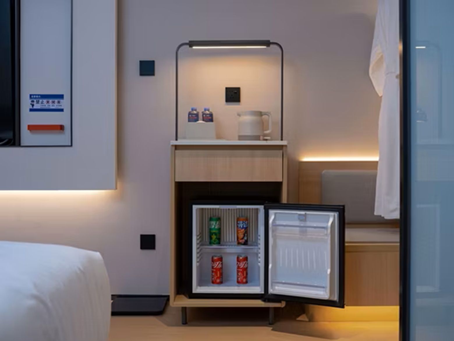 Habitació d'hotel petita amb un llit, una cuineta compacta que inclou nevera, microones i cafetera.