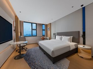Habitación de hotel moderna con una cama grande, un escritorio y vistas a la ciudad.
