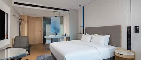 A modern hotel room with a large bed, a desk, and a bathroom.