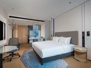 Una habitación de hotel moderna con una cama grande, un escritorio y un baño.