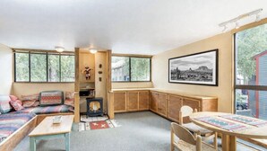 Ein gemütliches Wohnzimmer mit einer Couch, einem kleinen Tisch, einem Kamin und einer Essecke mit Stühlen.