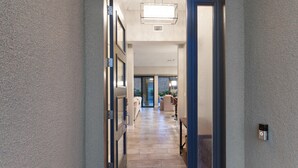 Un couloir avec un sol en pierre, une porte dotée d’un cadre bleu et un luminaire au plafond.