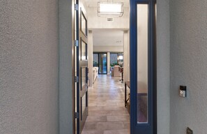 A hallway with a stone floor, a door with a blue frame, and a light fixture on the ceiling. - Three bedroom  house with beautiful pool (Lake Havasu City)