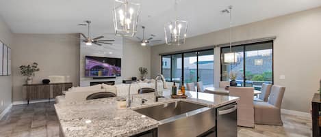 Una cocina moderna con encimeras de granito, electrodomésticos de acero inoxidable e iluminación colgante.