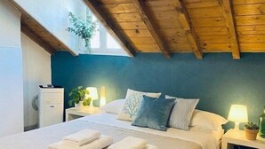 Een slaapkamer met een houten plafond, een bed met witte lakens, twee bedlampen en een raam met een plant.