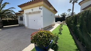 Een woonhuis met een garage, een verharde oprit en een verzorgd gazon.