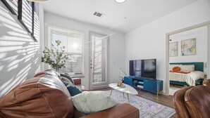 Ein modernes Wohnzimmer mit einer Ledersofa, einem Fernseher, einem kleinen Couchtisch und einer blauen Akzentwand.