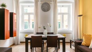 Zona pranzo con tavolo, sedie, un vaso con fiori e un divano.