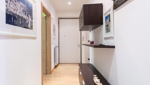 Un corridoio con pavimento in legno, una porta in fondo e un armadio in legno scuro con un quadro appeso al muro.