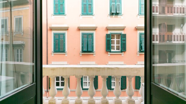 Facciata di un edificio con numerose finestre e balconi, caratterizzata da uno stile architettonico uniforme.