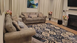 A living room with a sofa, a patterned rug, a fireplace, and a ceiling fan.