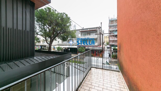 A modern building with a balcony, a tree, and a sign for 'immobiliare STELLA.' - Minetto / city center apt *Via Bafile* (Jesolo)