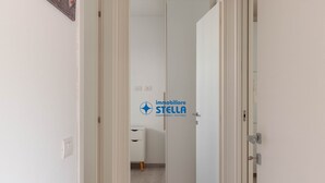 Un pasillo con una puerta blanca, un armario blanco y un logotipo en la pared.
