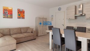 Una sala de estar moderna con sofá, mesa de comedor, sillas y una cocina con armarios y estufa.