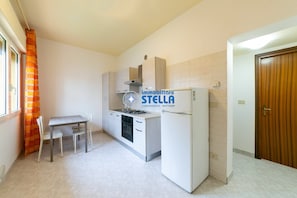Una cocina con una mesa de comedor, sillas, un refrigerador y una estufa.