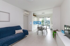 Ein modernes Wohnzimmer mit einer Couch, einem Esstisch, Stühlen und einem Fernseher.