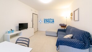 Un soggiorno moderno con un divano, una TV, una scrivania e una poltrona.