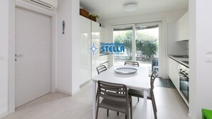 Una cucina moderna con mobili bianchi, un tavolo da pranzo con sedie e una finestra vista verde.