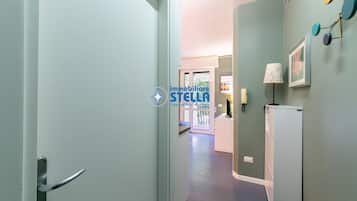 En hall med en dörr, ett kylskåp och en vägglampa.