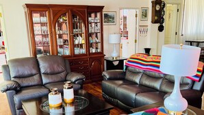 A living room with leather sofas, a coffee table, a cabinet with glass doors, and a colorful blanket on a chair. - Two minutes walk from the cable car🚡A spacious apartment ideal for families! (La Paz)