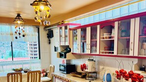 A kitchen with wooden chairs, a dining table, a microwave, a kettle, and cabinets with glass doors. - Two minutes walk from the cable car🚡A spacious apartment ideal for families! (La Paz)