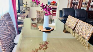 A dining area with wicker furniture, a glass-top table, and a vase with flowers. - Two minutes walk from the cable car🚡A spacious apartment ideal for families! (La Paz)