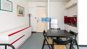 Moderni keittiö, jossa on valkoiset kaapit, punainen välitila ja musta ruokapöytä tuoleineen.