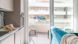 Una cocina moderna con comedor, un balcón con vista a un edificio y un sofá.