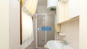 Ein Badezimmer mit Dusche, Toilette, Waschbecken und Handtuchhalter.