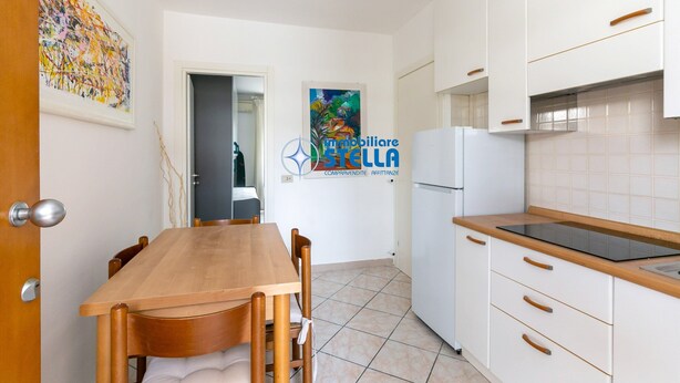 Eine Küche mit weißen Schränken, einem Holztisch und einem Kühlschrank.