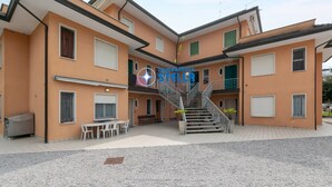 Ein mehrstöckiges Gebäude mit einer Treppe, Außenbestuhlung und einem sichtbaren Logo.