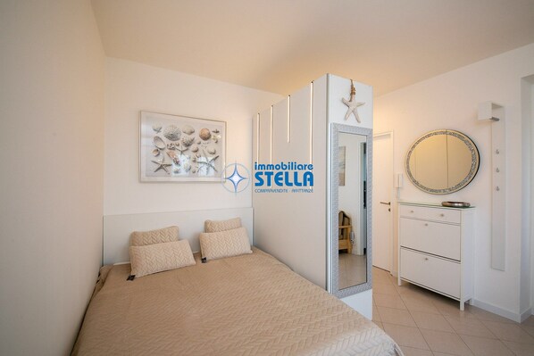 Une chambre à coucher avec un lit, une commode, un miroir et un tableau encadré accroché au mur.