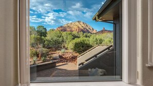 Vista a través de una ventana de un paisaje montañoso con árboles y cielo despejado.