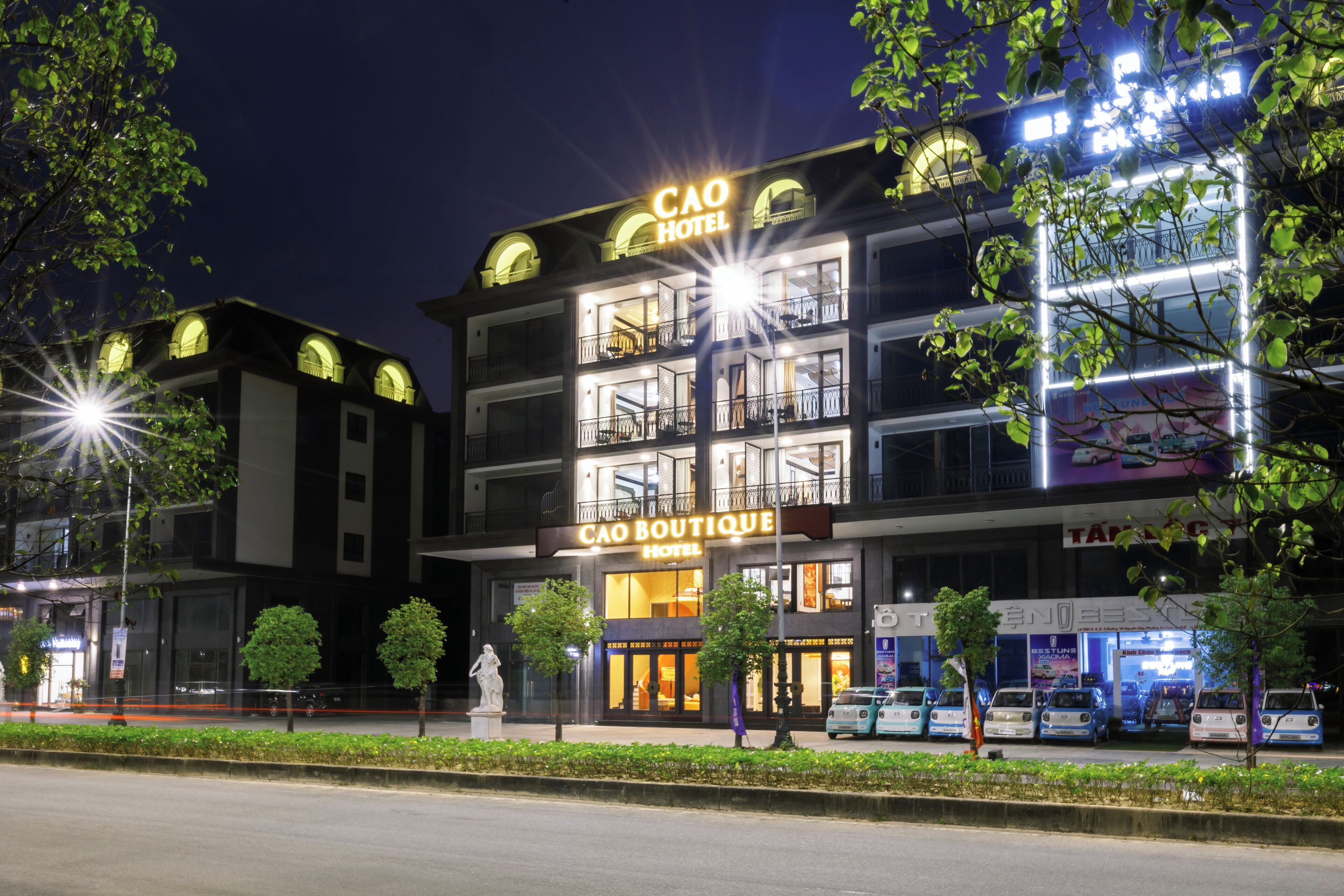 A hotel with a prominent sign, multiple balconies, and a well-lit facade.