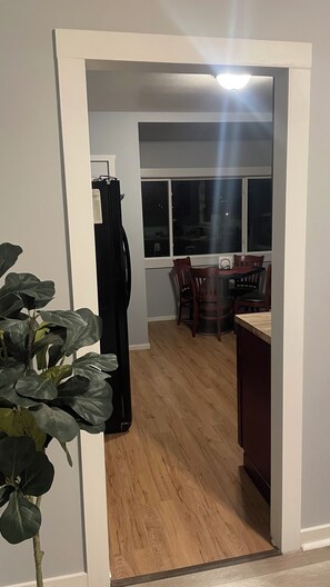 A hallway leading to a dining area with a table and chairs, a refrigerator, and a plant. - Convenient 2-bedroom House in downtown Bremerton Perfect for your Getaway (Bremerton)