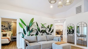 A modern living room with a grey sectional sofa, large green plants, and a wooden floor. - Palm Vista Luxury Resort • Heated Pool
• Near Theme Parks• 4BR/2BA (Davenport)