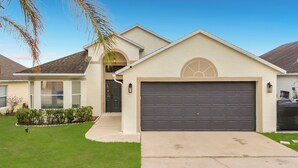A residential house with a garage, a front door, and a small porch. - Palm Vista Luxury Resort • Heated Pool
• Near Theme Parks• 4BR/2BA (Davenport)