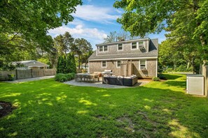A two-story house with a patio, outdoor furniture, and a well-maintained lawn. - Luxury 4br Cape Cod House, 5 Mins Beach, Pets OK, Sleeps 12, Fully Updated (Yarmouth)