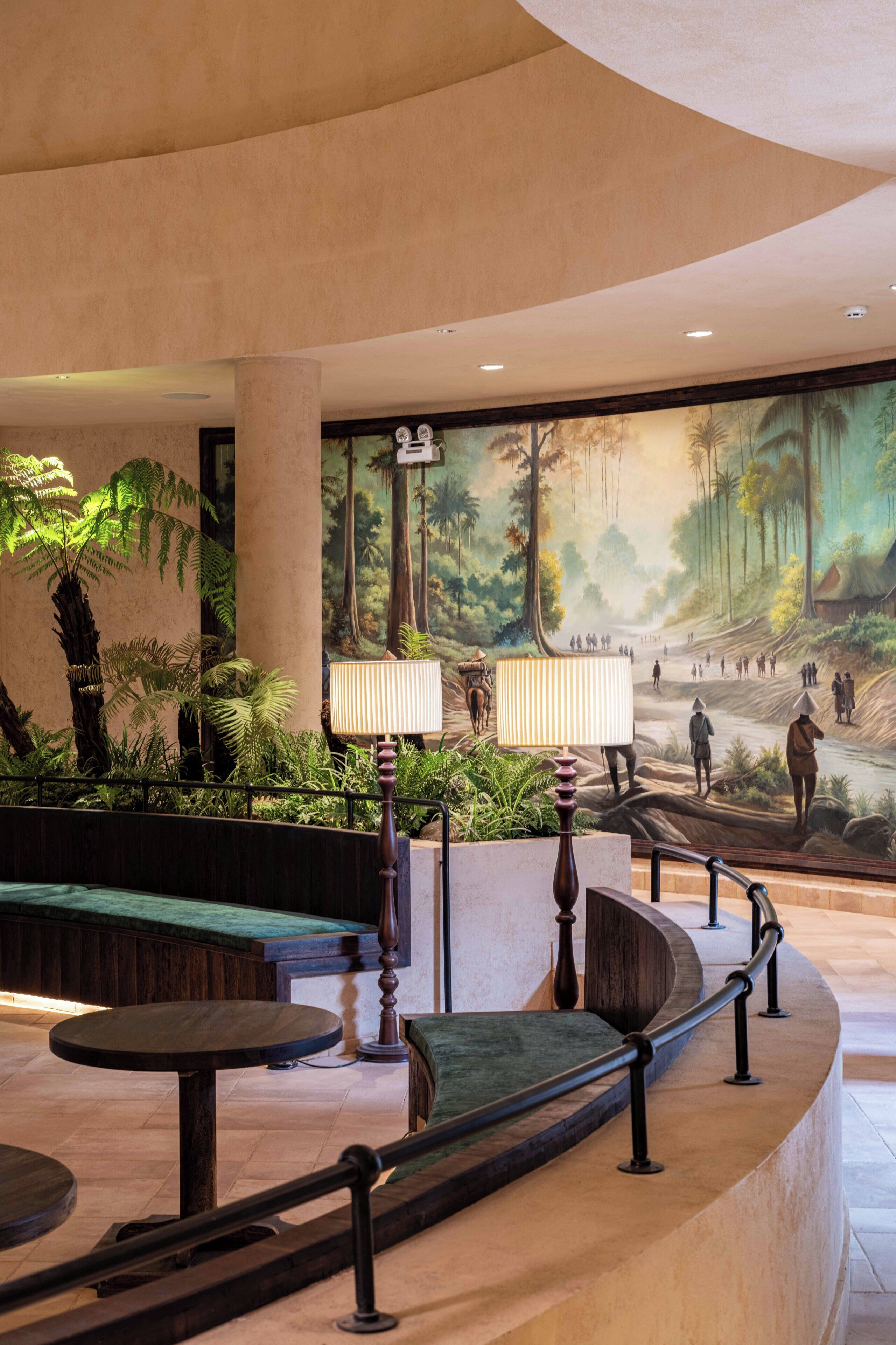 A lobby with a mural, seating area, and a staircase.