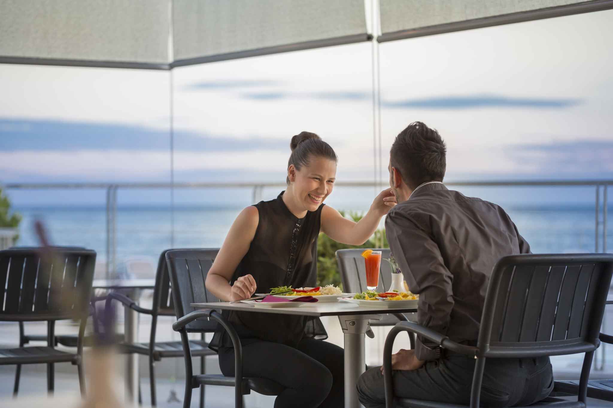 Two people dining at a table with a view of the ocean.