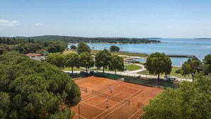 Una cancha de tenis con vistas a un lago y colinas.