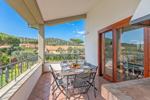 Un balcon avec une table dressée pour deux personnes, offrant une vue sur un paysage magnifique.