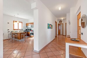 A modern kitchen with a central island, bar stools, and a dining table. - Villa Adriana Capalbio With A/c, BBQ and Parking (Capalbio)
