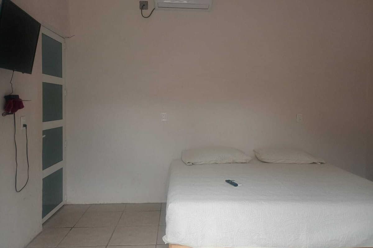 A bedroom with a bed, a television mounted on the wall, and a wardrobe.