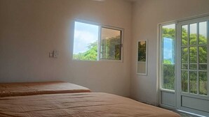 A room with two beds, a ceiling fan, a window, and a door leading outside. - Hospedaje ojo de agua (Santiago Laollaga)