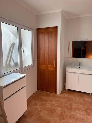 Un bagno con un lavandino bianco, uno specchio e una porta in legno.