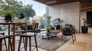 A modern lounge area with wooden furniture, a glass coffee table, and potted plants. - Casa Grace a pasos de Polanco y Reforma. (Ciudad de México)