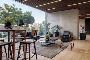 A modern lounge area with wooden furniture, a glass coffee table, and potted plants. - Casa Grace a pasos de Polanco y Reforma. (Ciudad de México)